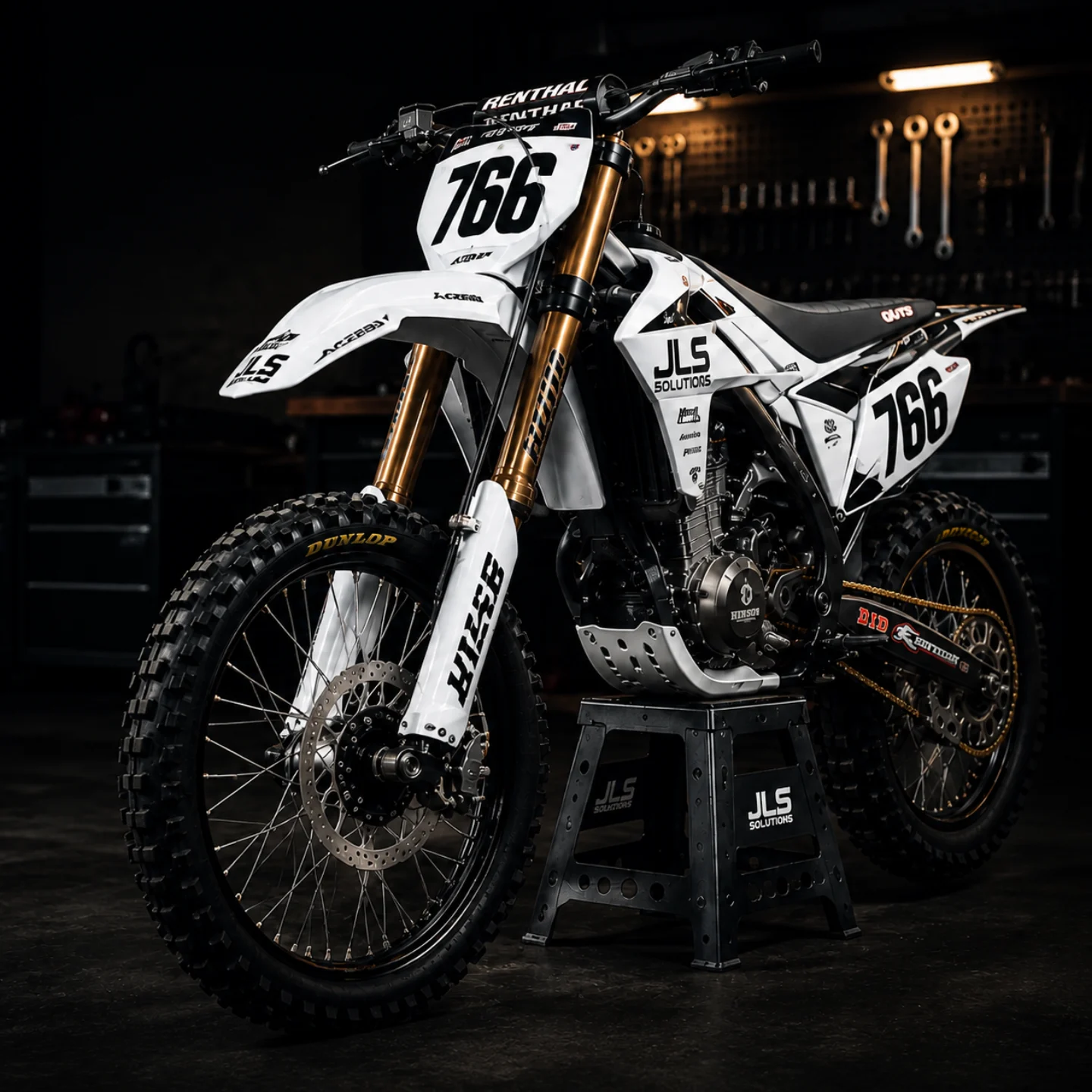 White factory-style motocross bike number 766 with gold forks in a dark workshop