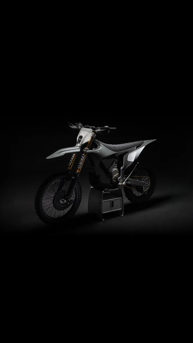 Stark Varg electric dirt bike on a stand, lit against a black background, gold Kayaba forks and the motor housing visible where a combustion engine would sit